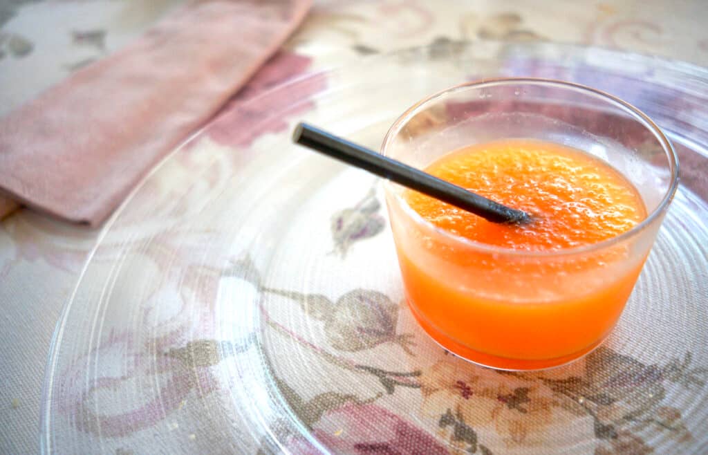 Agua de Valencia cocktail with a straw on a floral tablecloth.

